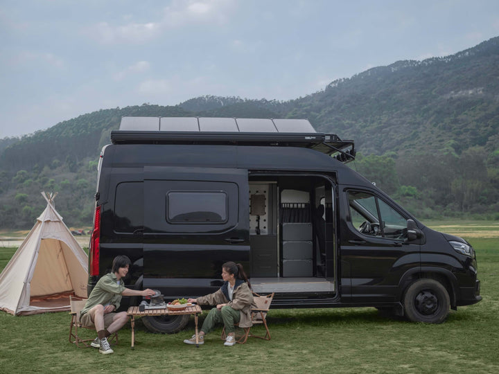 Black camper van with EcoFlow Power Kit and solar panels, parked by tent in green field, ideal for off-grid living and van life adventures.