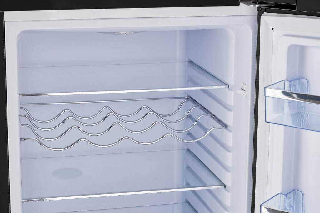 Inside view of Unique 9 cu/ft retro bottom mount refrigerator with metal shelving and door storage.