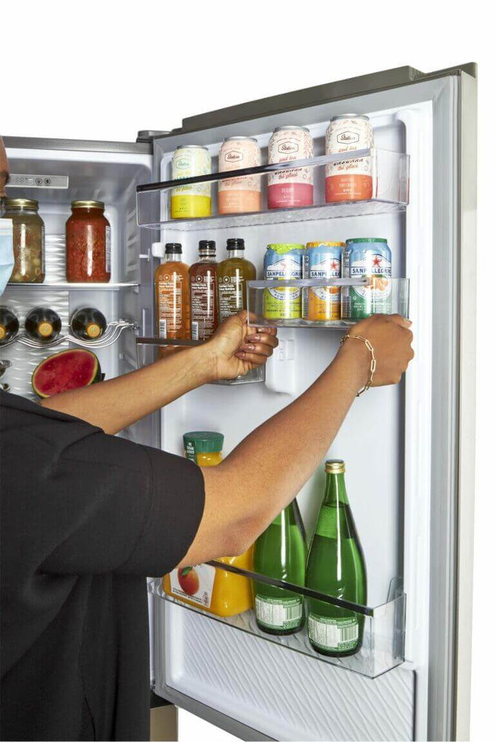 Person organizing drinks in a Unique Prestige electric bottom-mount refrigerator door shelves.