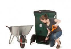 Woman using Biolan Biowaste 220 Eco Composter from Cabin Depot with wheelbarrow, showcasing efficient composting process.